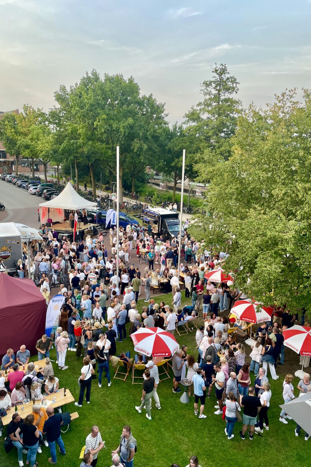 Viele Menschen auf einer Wiese mit Gläsern in der Hand.