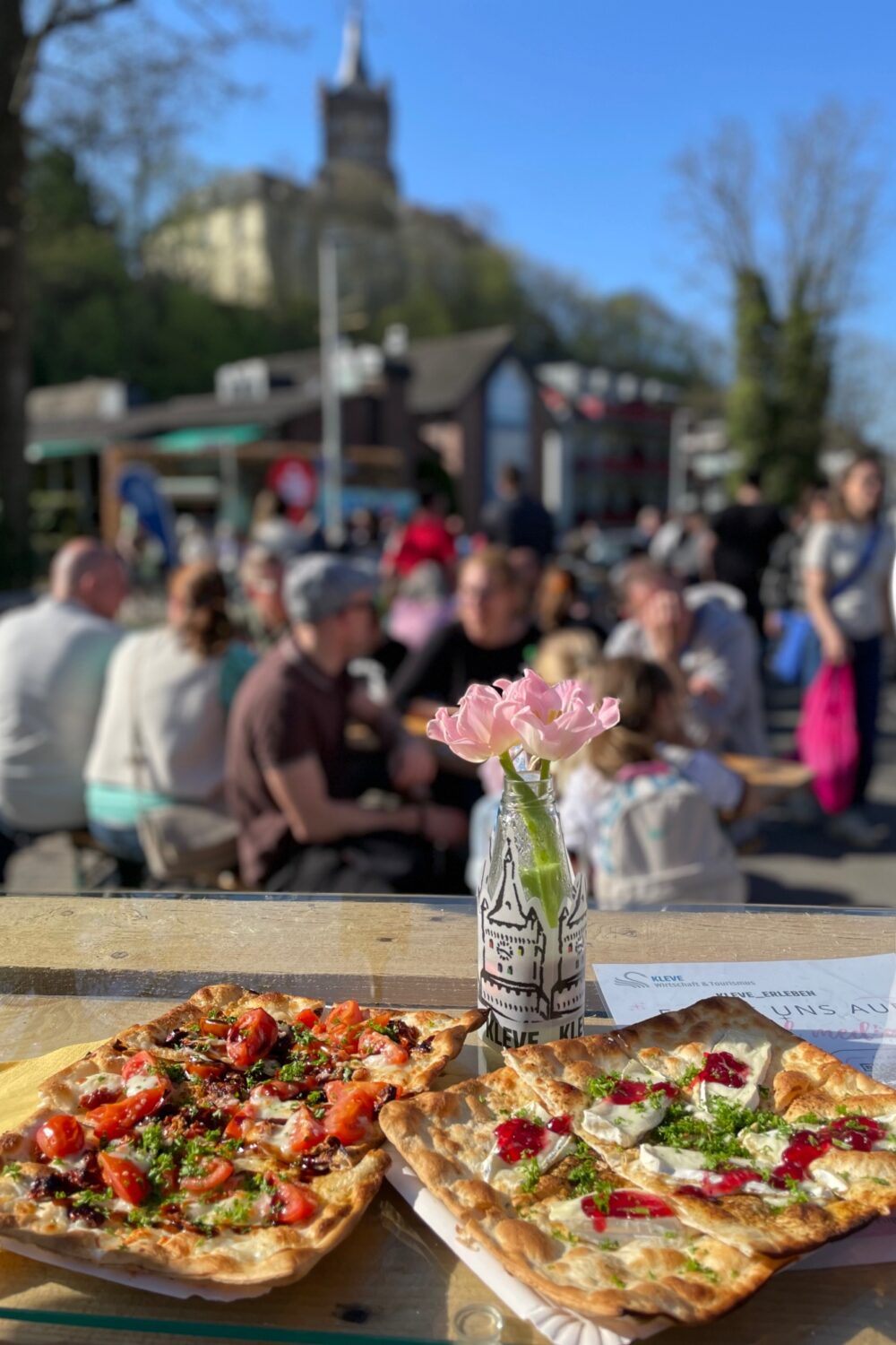 Zwei Flammkuchen auf einem Holztisch.