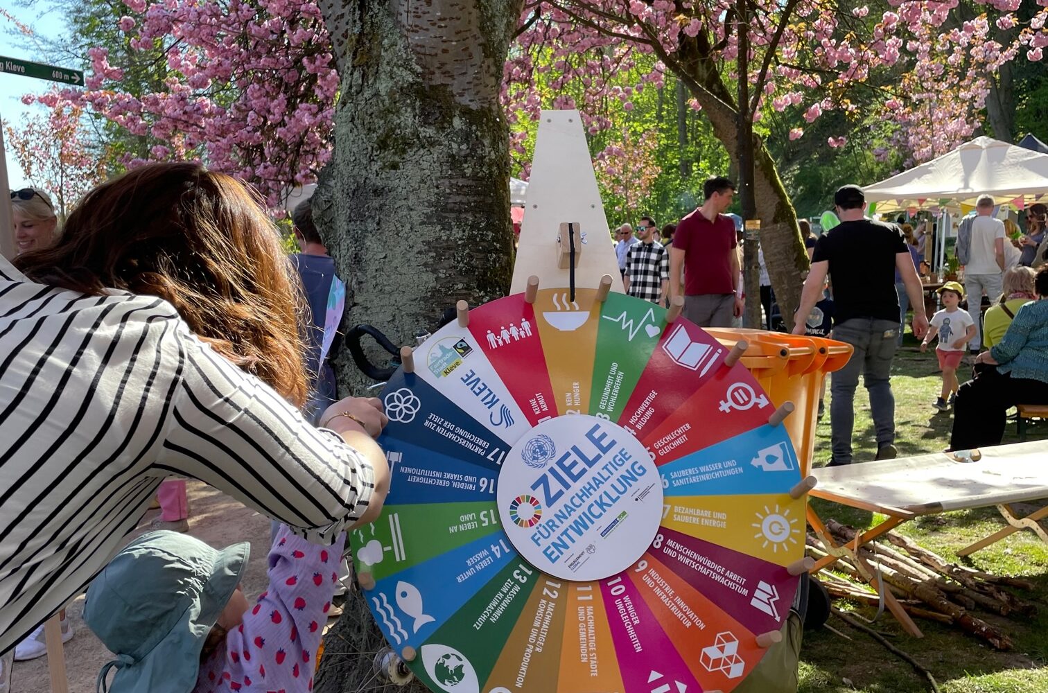 Frau und Kind drehen an einem Glücksrad.