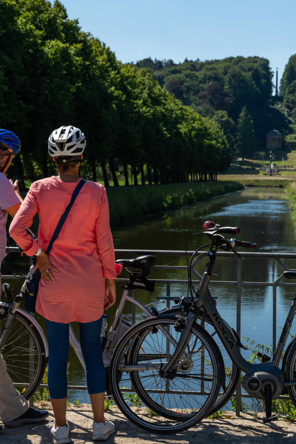 Ein männlicher und ein weiblicher Fahrradfahrer stehen in den barocken Gartenanlagen.