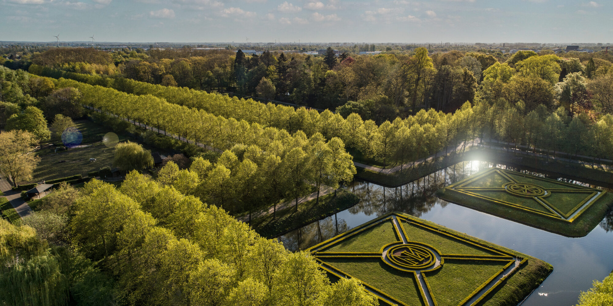 Vogelperspektive auf die Gartenanlagen mit den schnurgerade Baumalleen und dem Moritzkanal