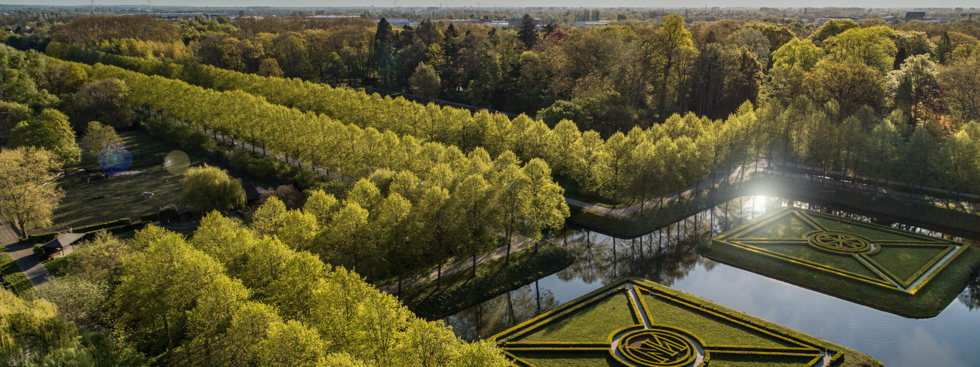 Vogelperspektive auf die Gartenanlagen mit den schnurgerade Baumalleen und dem Moritzkanal