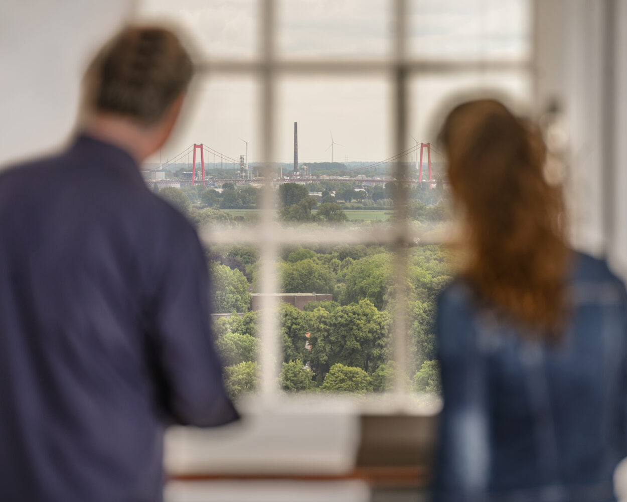 Zwei Personen aus dem Fenster der Schwanenburg. Die Rheinbrücke ist im Hintergrund.