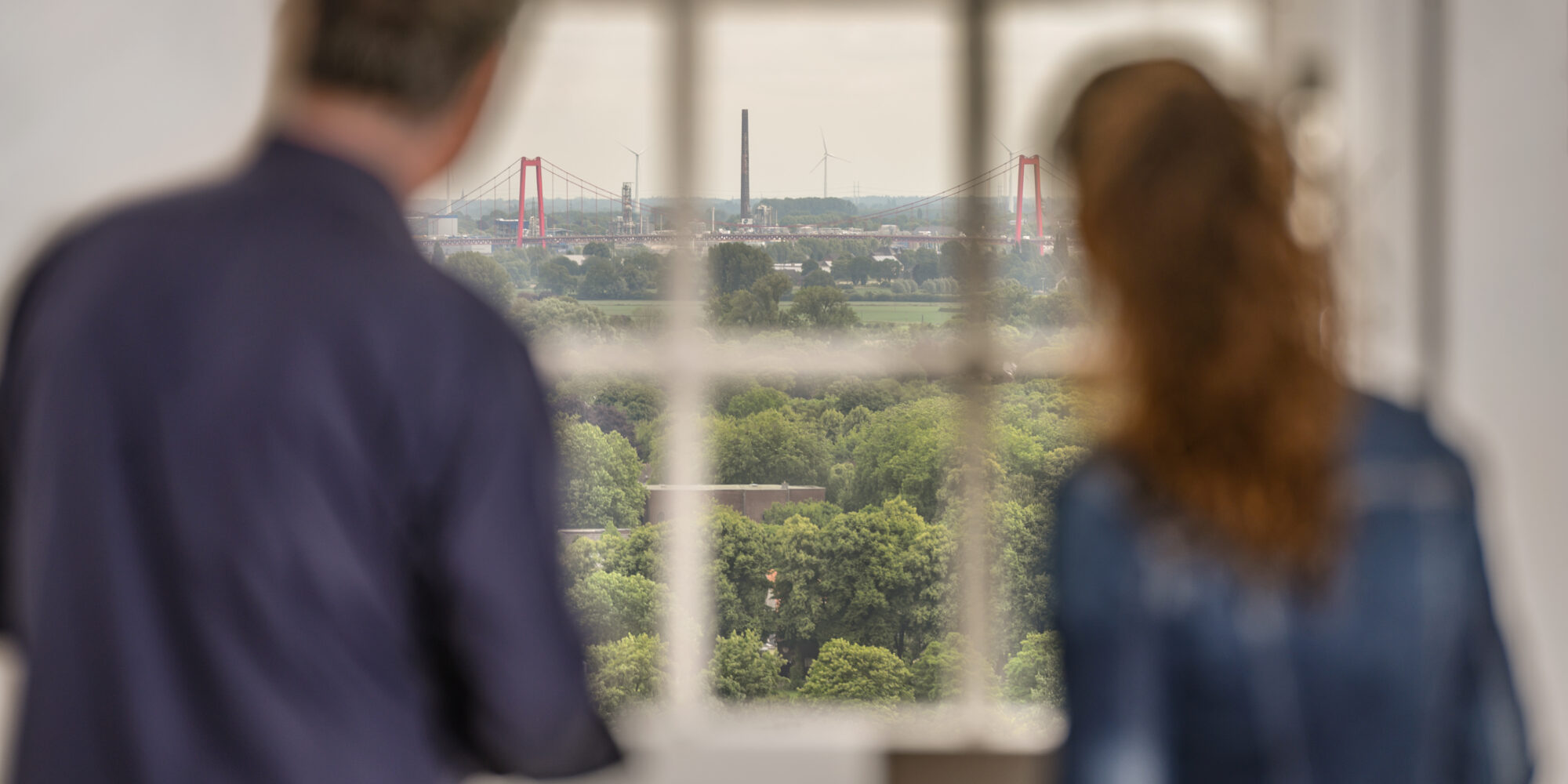Zwei Personen aus dem Fenster der Schwanenburg. Die Rheinbrücke ist im Hintergrund.