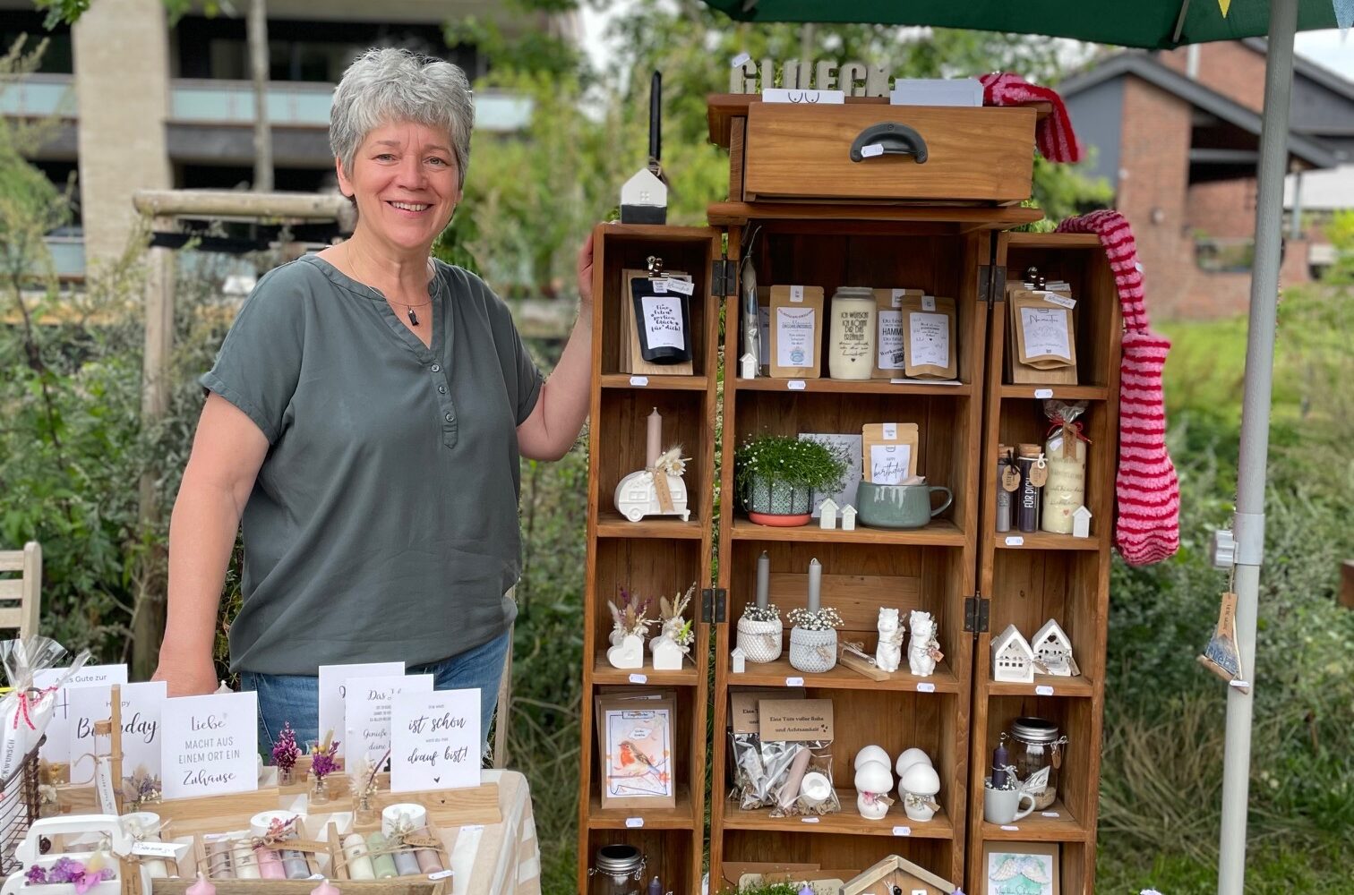 Frau neben kleinen Holzregal mit Produkten