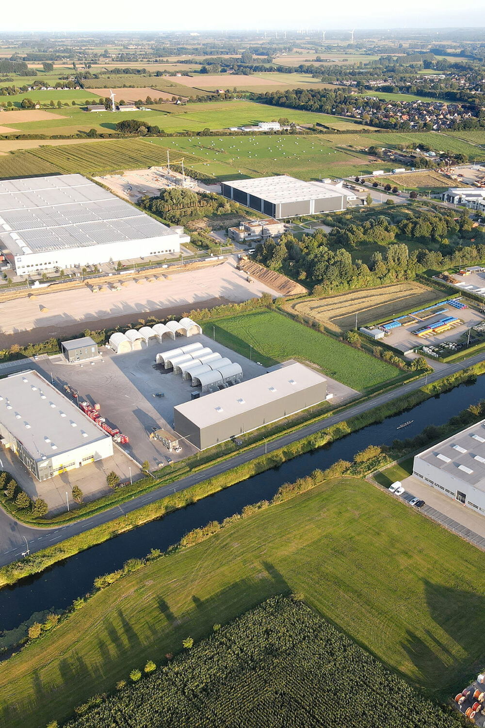 Luftaufnahme des Industriegebiets Nellenwardgen/Hammscher Hof mit mehreren großen Lagerhallen, umgeben von Feldern und einem Kanal im Vordergrund.