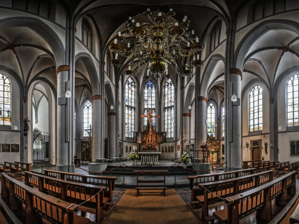 Innenansicht der Stiftskirche mit Pfeilern, Bögen und Altar.