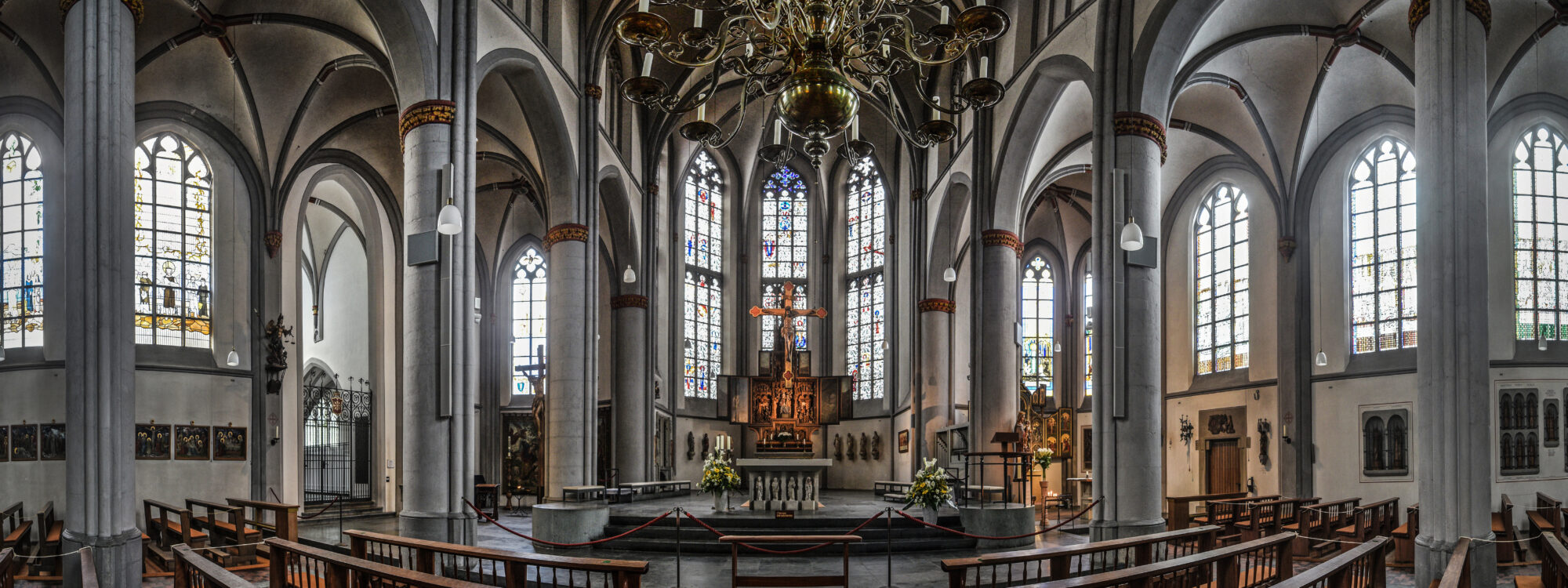 Innenansicht der Stiftskirche mit Pfeilern, Bögen und Altar.