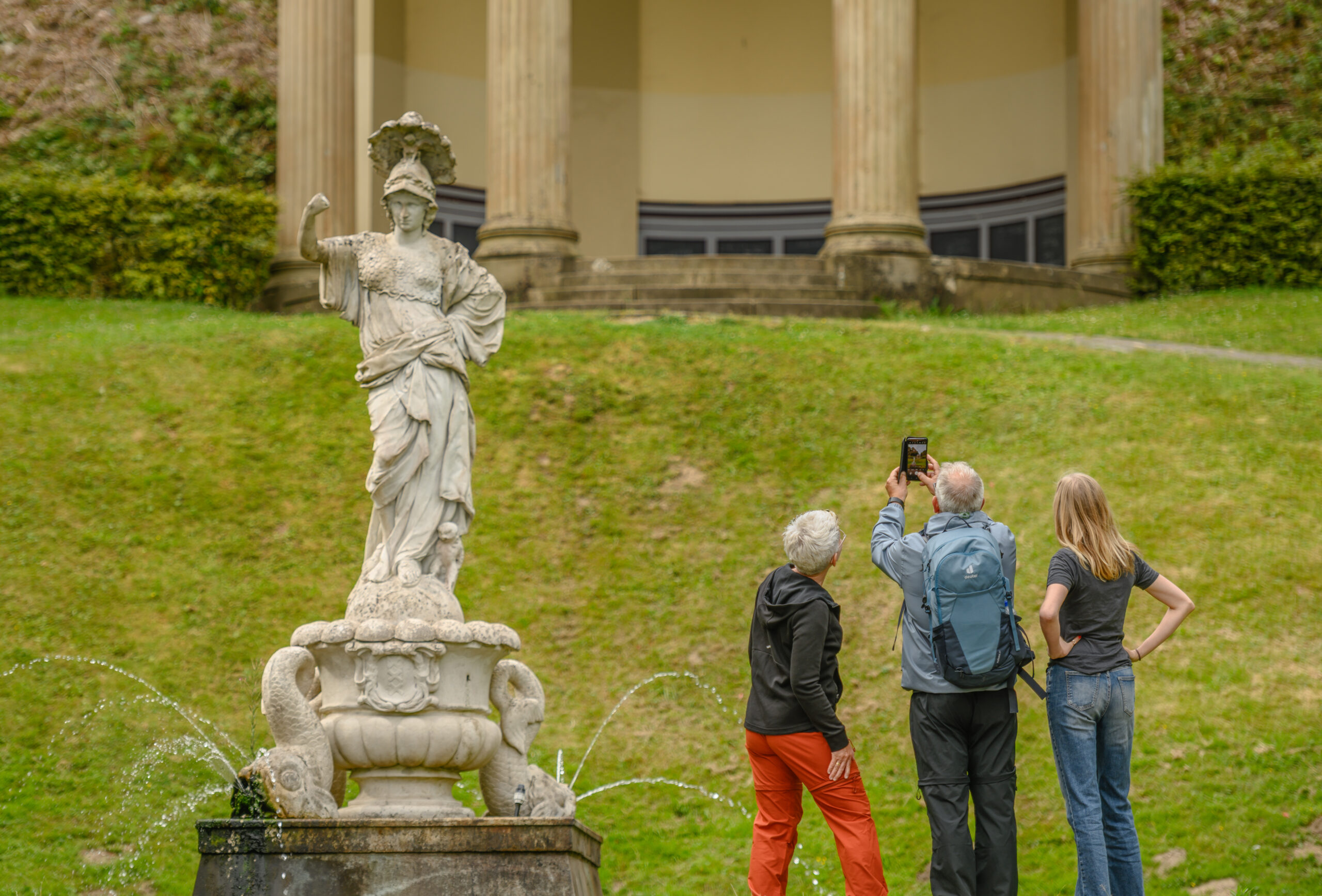 Zwei Frauen und ein Mann schauen sich eine Skulptur an.