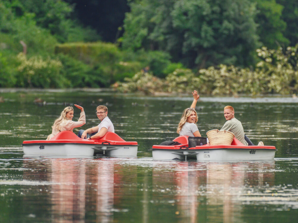 Vier junge Menschen auf Tretbooten im Wasser