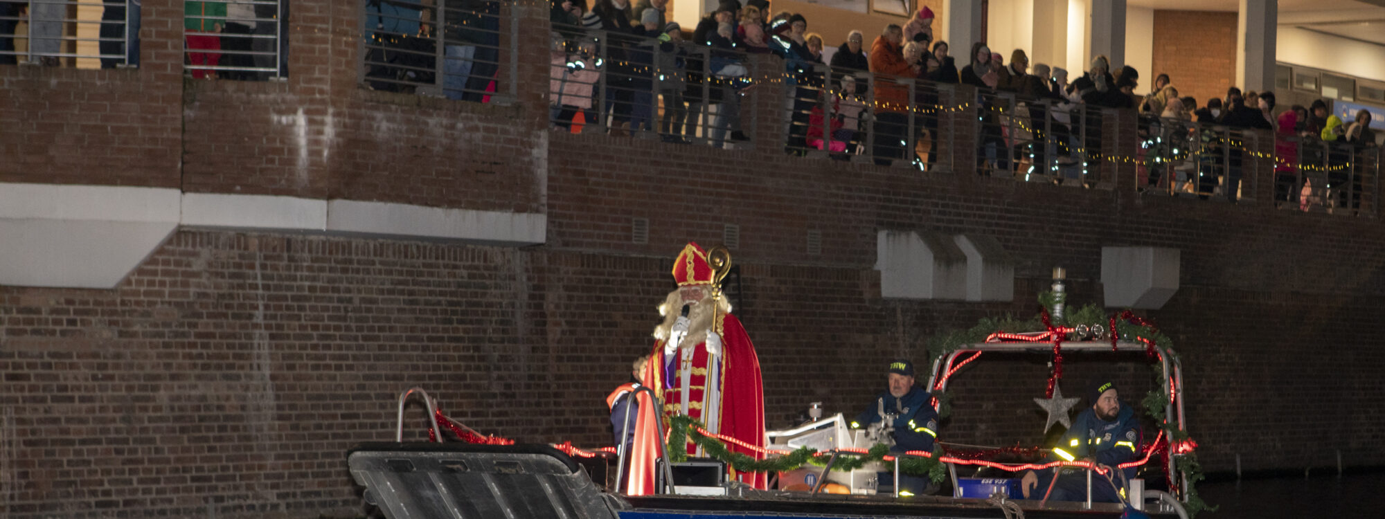 Mann verkleidet als Nikolaus fährt auf einem Boot über einen Fluss.