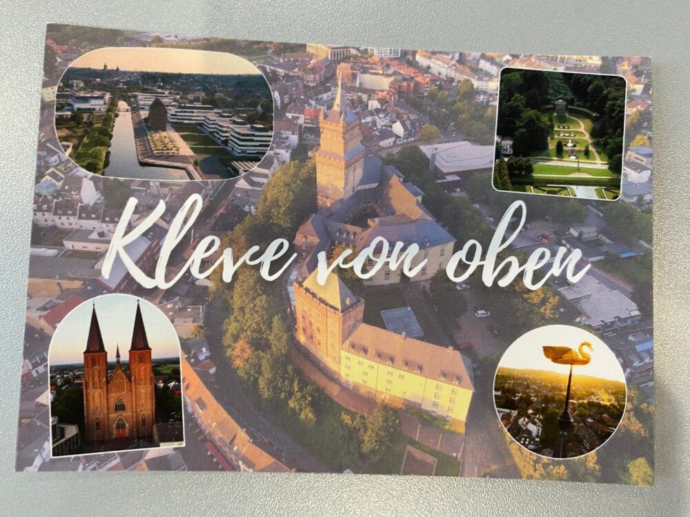 Luftaufnahme der Stadt Kleve mit Schloss und mehreren kleineren Fotos von Gebäuden und einem Wetterhahn bei Sonnenuntergang, Text 'Kleve von oben'.