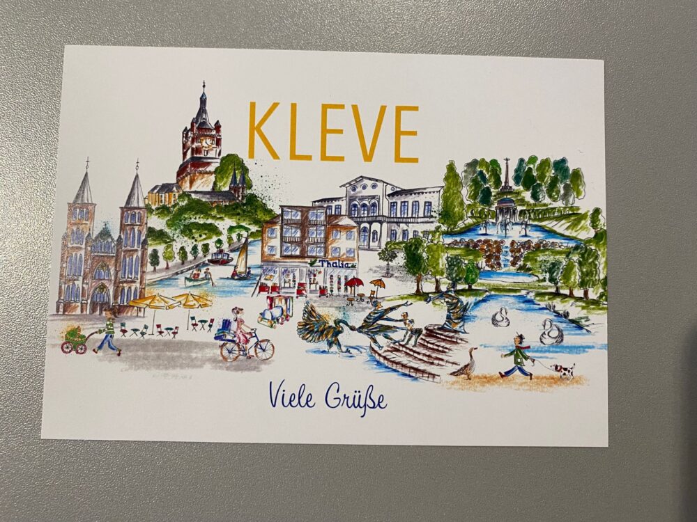Bunte Zeichnung der Stadt Kleve mit historischen Gebäuden, Park mit Brunnen, Menschen auf Fahrrädern und zu Fuß, Text 'KLEVE' und 'Viele Grüße'.