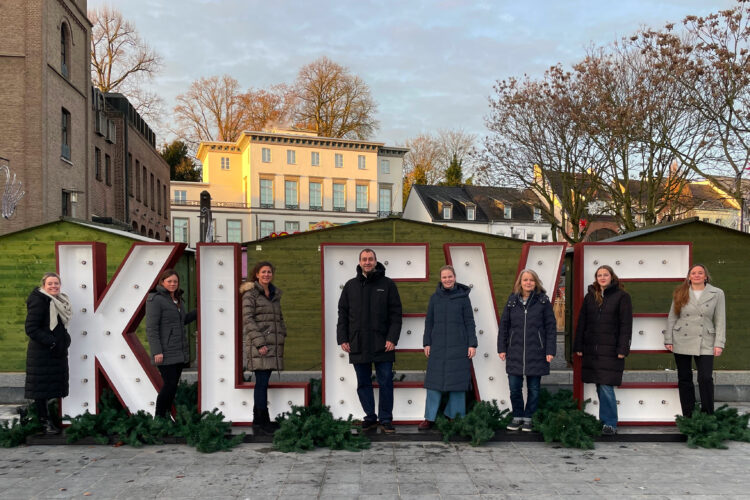 Mitarbeiter der WTM stehen vor einem großen KLEVE-Schriftzug, im Hintergrund Haus Koekkoek