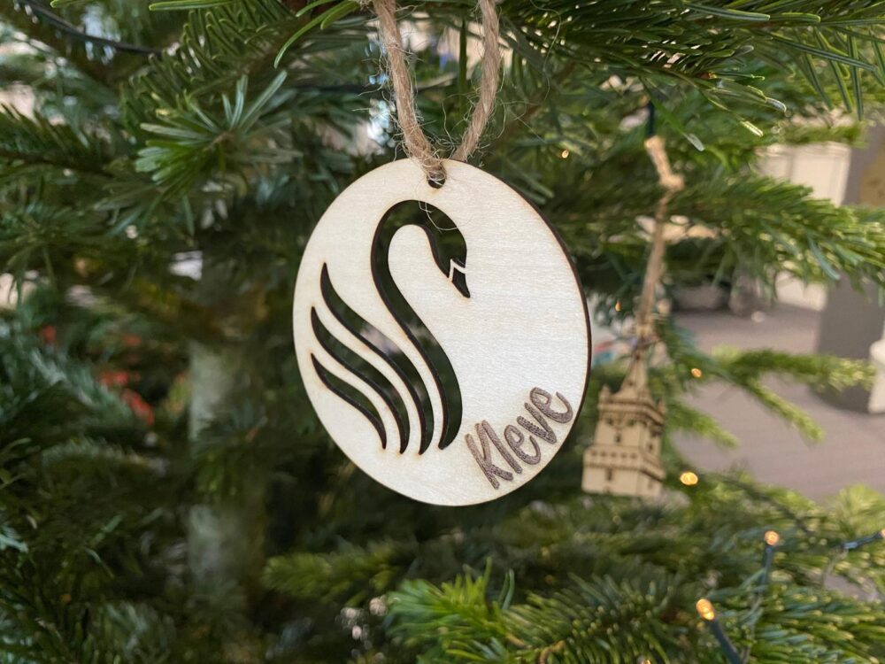 Dekoanhänger mit einem ausgestanzten Schwan hängt an einem Tannenbaum, unten steht Kleve eingraviert
