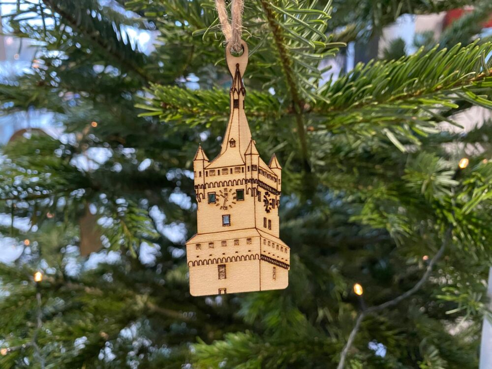 Anhänger in Form der Klever Schwanenburg aus Holz hängt an einem Tannenbaum
