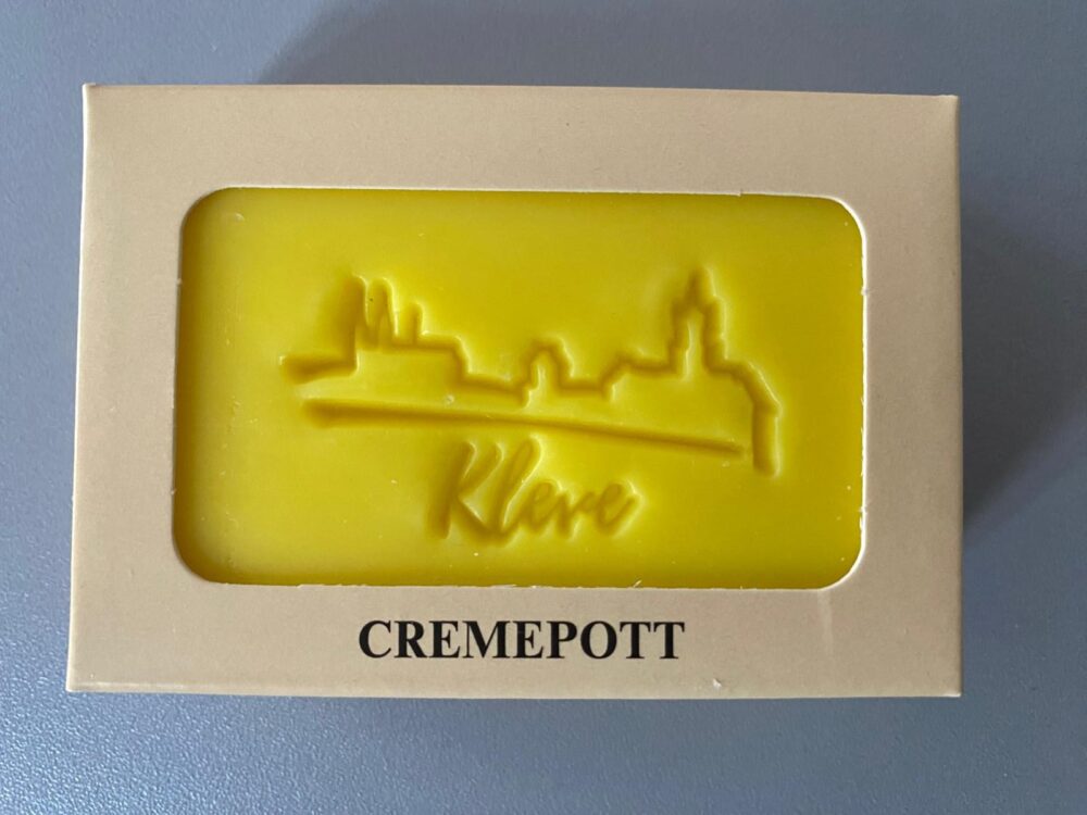 Gelbe Seife mit geprägter Stadtsilhouette und Schriftzug „Klever" in einer hellen Verpackung mit Aufdruck „CREMEPOTT"
