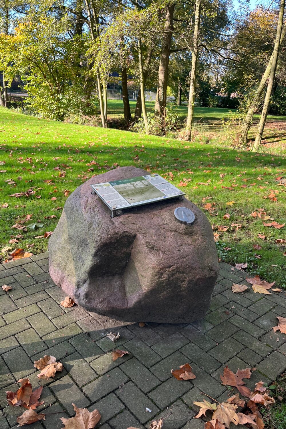 Findling mit Infotafel im Grünen