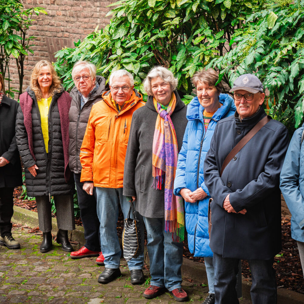 Eine Gruppe von Stadt- und Gästeführern steht vor einer begrünten Wand