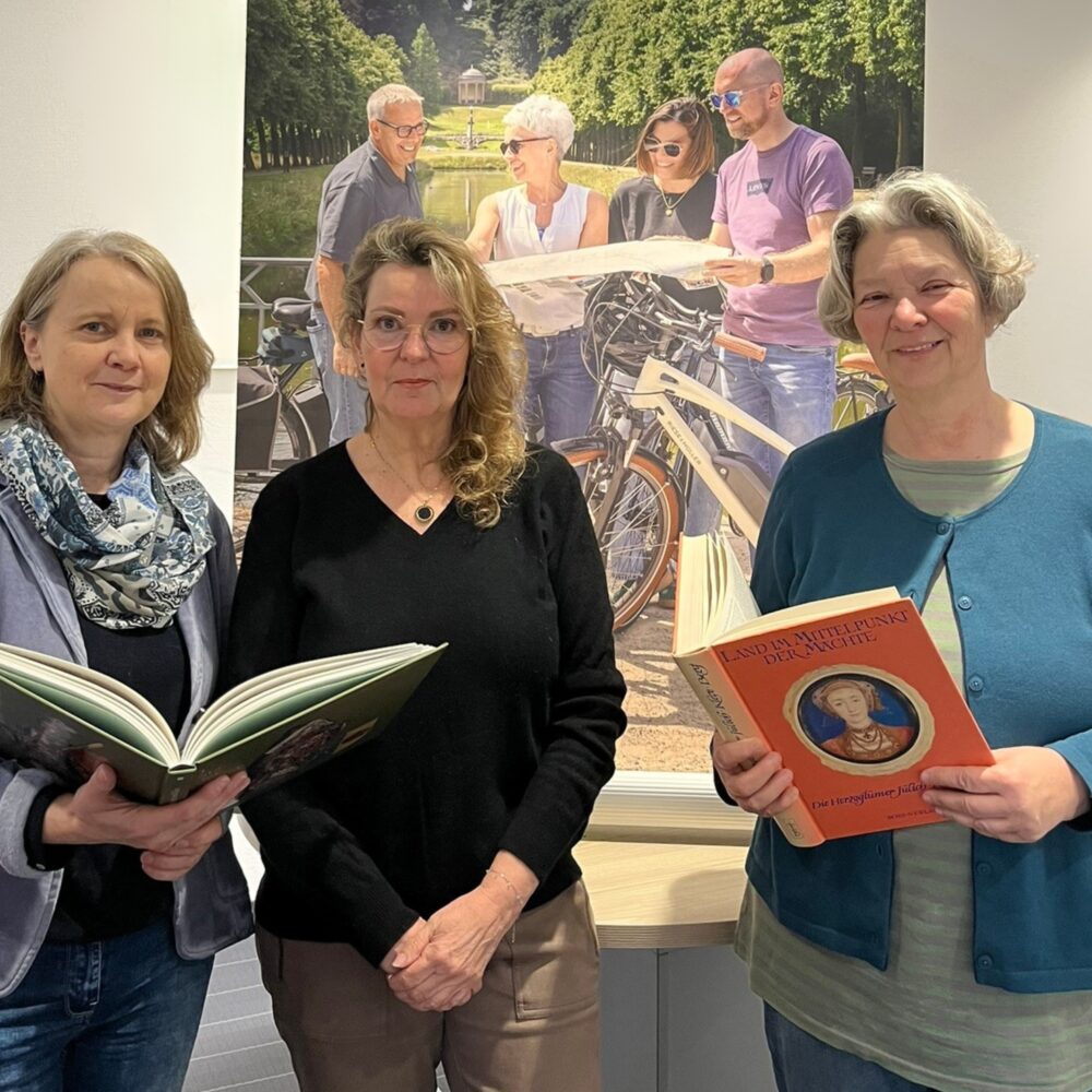 Drei Frauen mit dicken Büchern in der Hand werben für die Stadtführerqualifizierung
