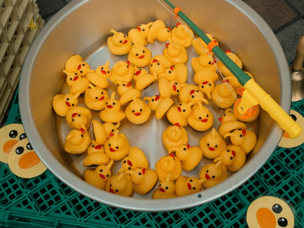 Viele gelbe Gummienten in einem großen runden Behälter mit einer Angelrute darüber