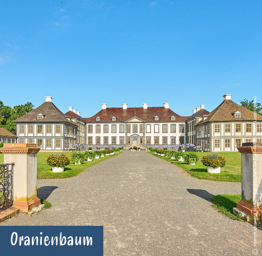 Barockes Schloss mit symmetrischem Aufbau und Gartenweg im Vordergrund unter blauem Himmel