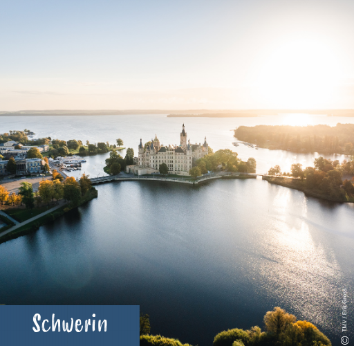 Luftaufnahme des Schweriner Schlosses auf einer Insel im See bei Sonnenaufgang