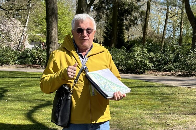 Ein Mann in einem Park, der eine Abbildung zeigt und etwas erklärt