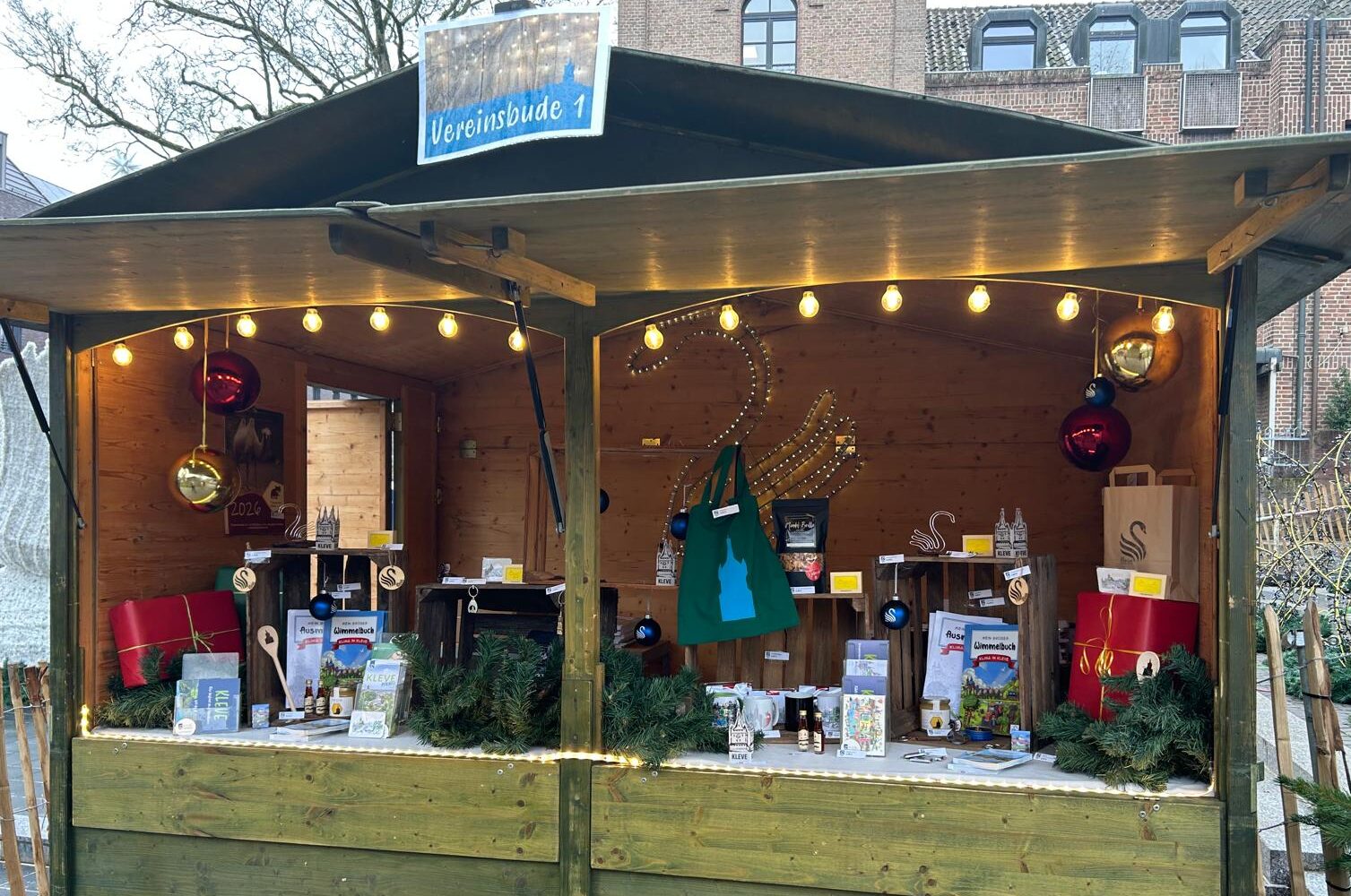 Holzstand mit Weihnachtsdekoration, Geschenken und einem Schild mit der Aufschrift 'Vereinsbude 1'