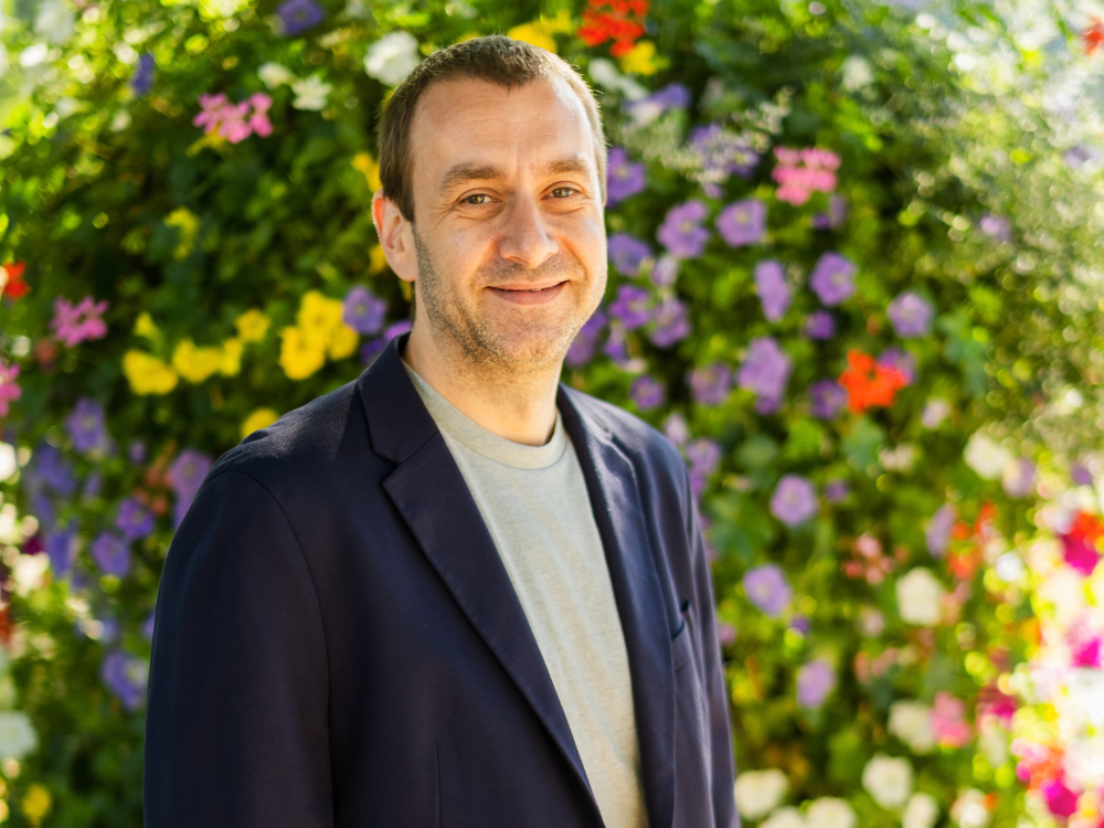 Tobias Nelke im Vordergrund, im Hintergrund sind bunte Blumen