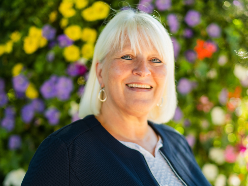 Nicole Pauls im Vordergrund, im Hintergrund sind bunte Blumen