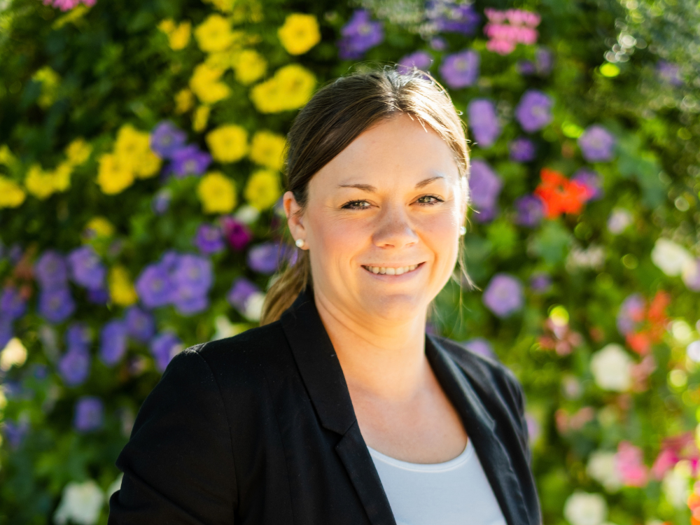 Karina van Kevelaer im Vordergrund, im Hintergrund sind bunte Blumen