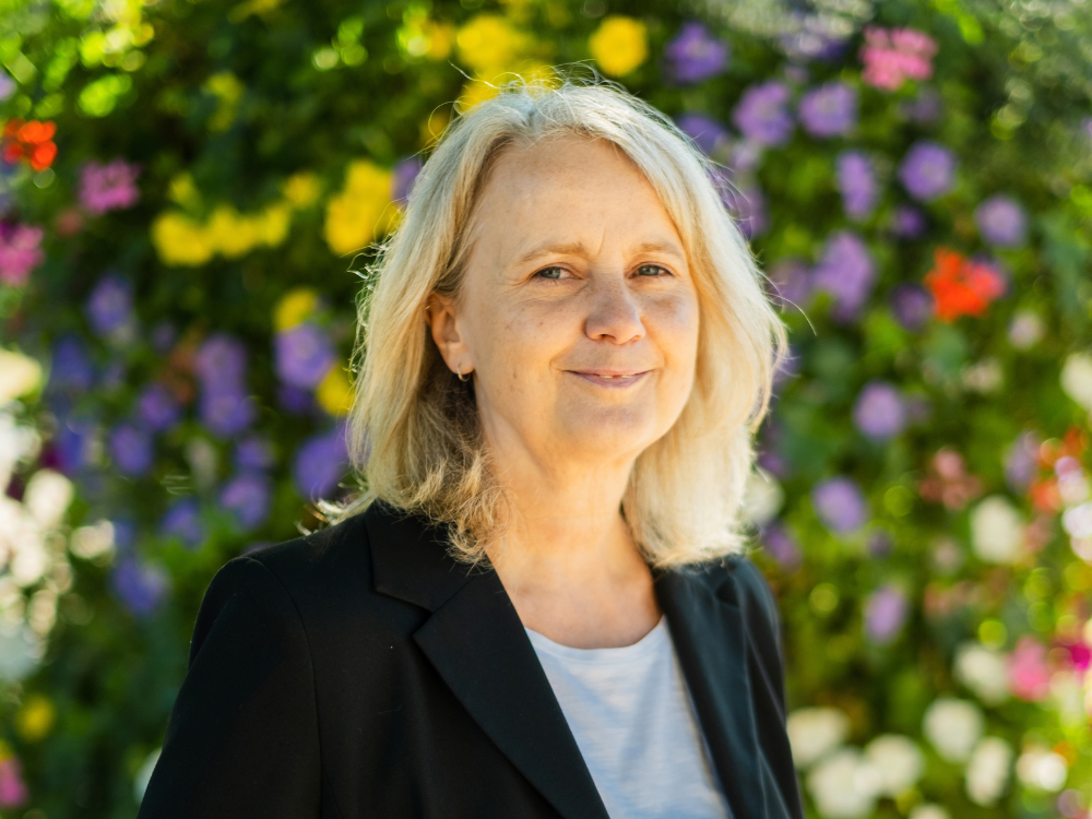 Martina Gellert im Vordergrund, im Hintergrund sind bunte Blumen