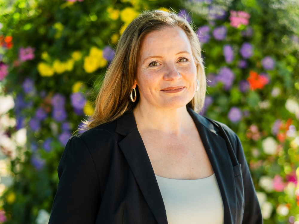 Mina van Lutterveld im Vordergrund, im Hintergrund sind bunte Blumen